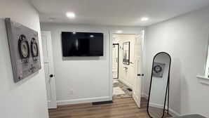 Un dormitorio con cama, ventilador de techo, televisión de pantalla plana y espejo.