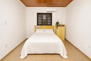 A bedroom with a bed, a window, a dresser, and an air conditioning unit. - Charming Chalet in the Penedo Mountains (Itatiaia)