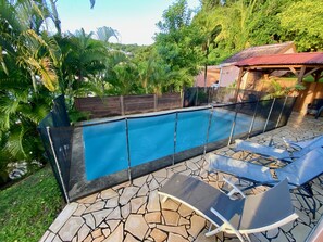 A swimming pool with a stone-tiled deck and lounge chairs. - Sea and pool view, fully equipped villa for 8 (Les Trois-Ilets)