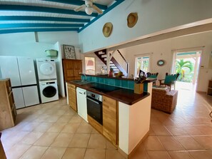 A spacious kitchen with a central island, built-in appliances, and a view to a dining area. - Sea and pool view, fully equipped villa for 8 (Les Trois-Ilets)
