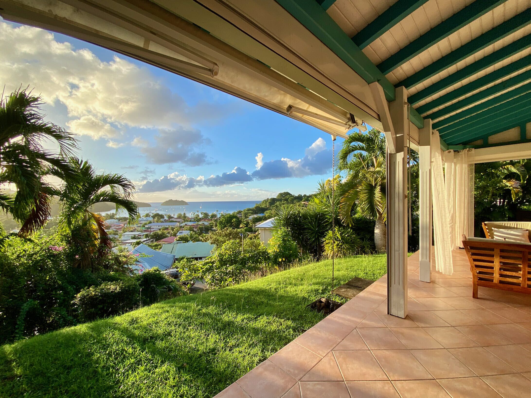 A covered outdoor area with a view of a coastal town, greenery, and a clear sky.