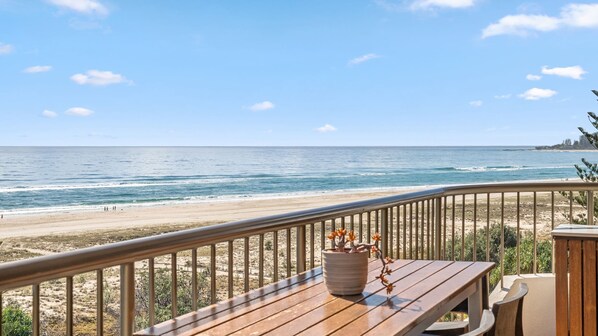 Een houten terras met een balustrade, met uitzicht op een strand.