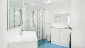 A modern bathroom with a glass-enclosed shower, a white sink, and a mirror above the sink. - Porta Pacifique 19 - Beachfront Bilinga - Min. 3 Night Stays - Linen Provided (Bilinga)