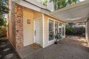 A house with a brick exterior, a white door, and a covered porch area. - Charming 2BR Home | Fireplace & Outdoor Lounge (Abilene)
