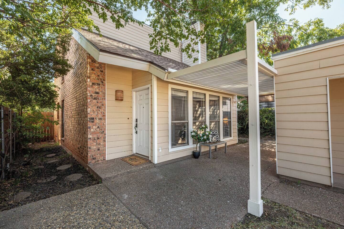 A residential property with a brick exterior, a covered porch, and a small garden area.