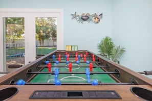 Ein Kicker mit einer grünen Spielfläche und roten sowie blauen Spielfiguren.