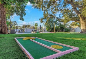 Ein Rasenstück mit einem Shuffleboard-Tisch und einem Pool im Hintergrund.