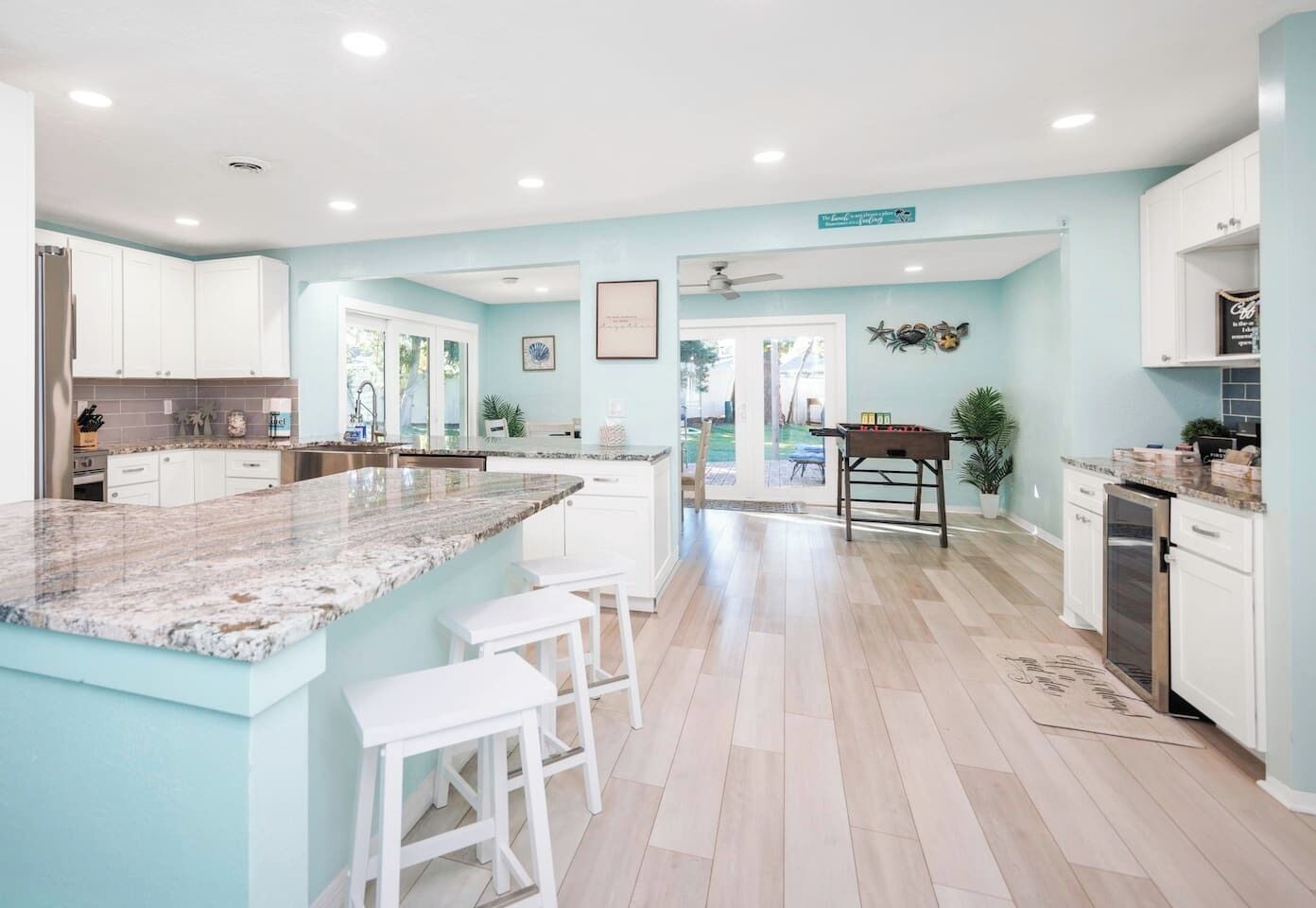 A modern kitchen with white cabinets, a granite countertop, and a dining area with a table and chairs.