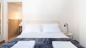 A hotel room with a bed, a bedside table with a lamp, and a door leading to another room. - Marghera Smart Stay 1 | A Comfortable Room in Venice (Marghera)