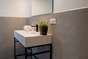 Ein modernes Badezimmer mit einem weißen Waschbecken, einem Handtuch und einem Blumentopf.