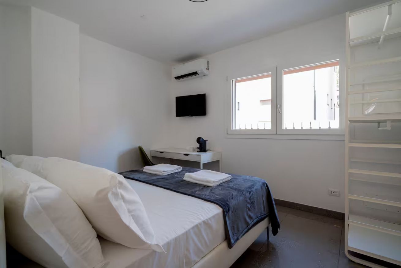 Una camera da letto con un letto, una scrivania, una televisione e una finestra.