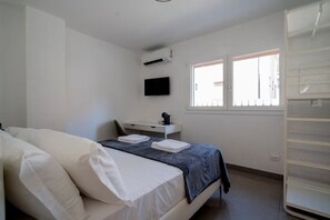 Una camera da letto con un letto, una scrivania, una televisione e una finestra.