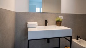 A modern bathroom with a white sink, black faucet, and a potted plant. - Marghera Smart Stay 1 | A Comfortable Room in Venice (Marghera)