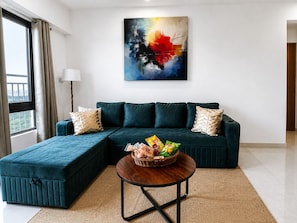 A modern living room with a sectional sofa, a round coffee table, and a colorful abstract painting on the wall. - Premium 2-bedroom apartment in the hearts of Mumbai! (Mumbai)