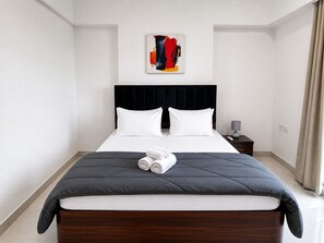 A hotel room with a large bed, a headboard, a nightstand, a lamp, and a painting on the wall. - Premium 2-bedroom apartment in the hearts of Mumbai! (Mumbai)