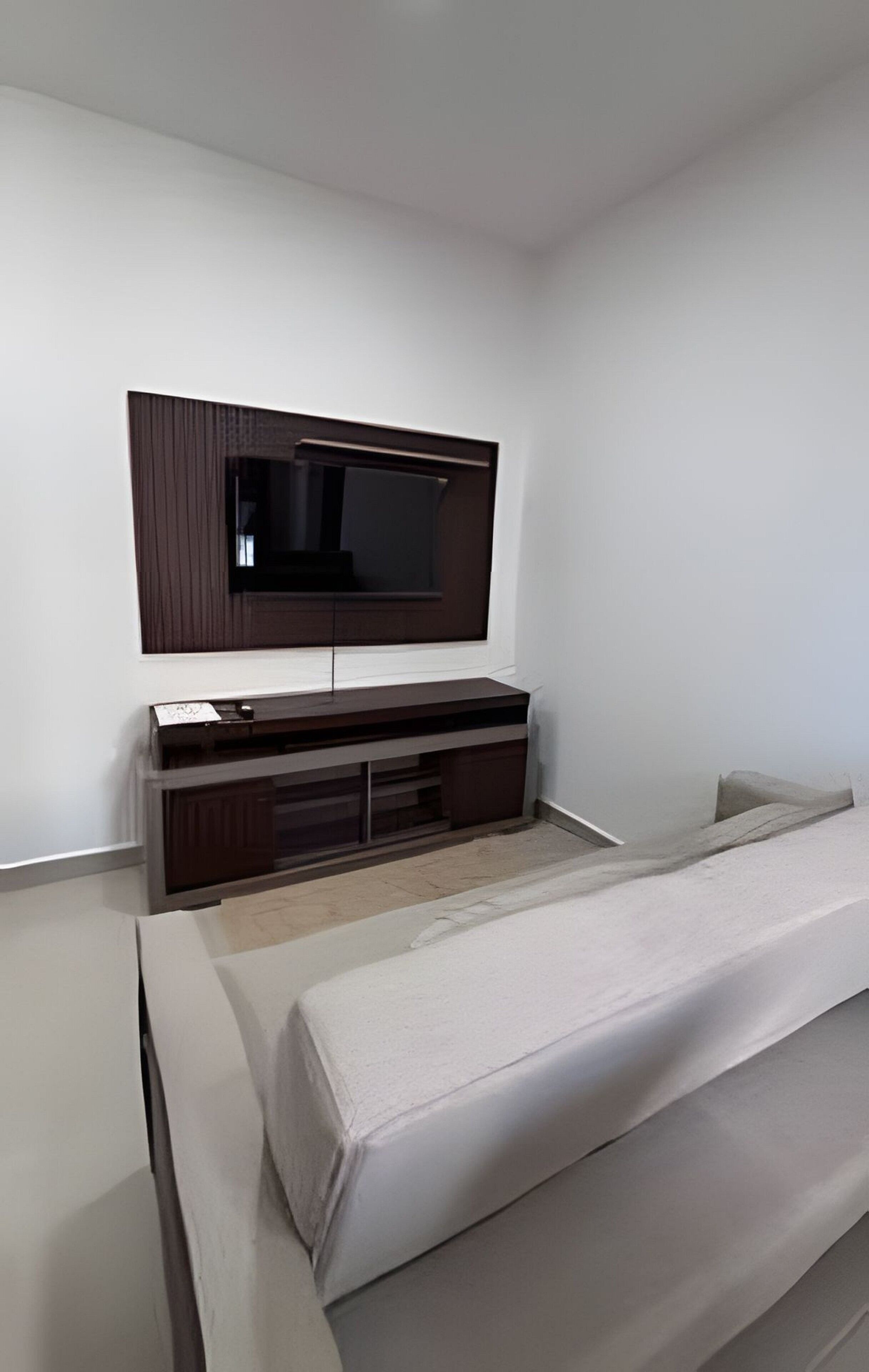 Un dormitorio moderno con una cama grande, un televisor de pantalla plana en la pared y un diseño minimalista.