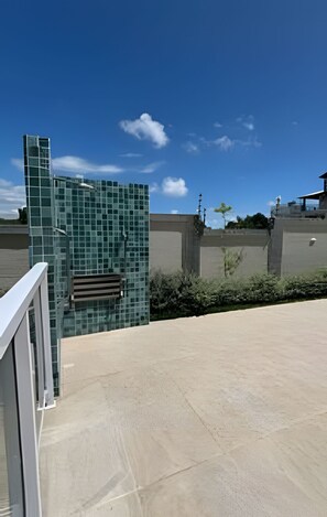 A modern building with a glass facade, a concrete wall, and a clear blue sky. - Apto 2 Qtos I Suíte I Lazer completo (Cabedelo)