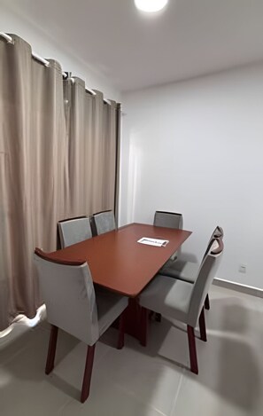A conference room with a rectangular table, four chairs, and a window with curtains. - Apto 2 Qtos I Suíte I Lazer completo (Cabedelo)
