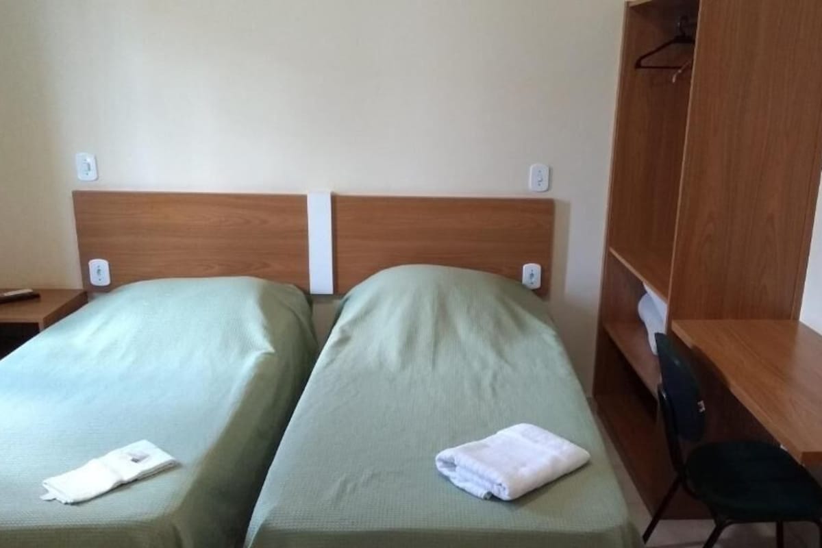 A room with two single beds, a wooden desk, and a chair.