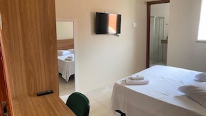 Ein Hotelzimmer mit einem Bett, einem an der Wand montierten Fernseher und einer Duschkabine.
