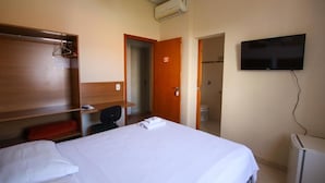 Ein Hotelzimmer mit einem Bett, einem Schreibtisch, einem Fernseher und einem Kleiderschrank.