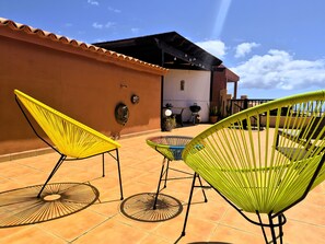Eine Terrasse mit zwei Stühlen, einem Tisch, einem Grill und einem Blumentopf.