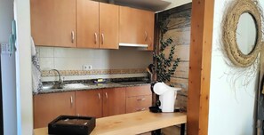 Eine Küche mit Holzschränken, einer Granit Arbeitsplatte, einer Spüle und einem weißen Wasserkocher.