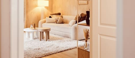 Een moderne woonkamer met een bank, salontafel en lamp.