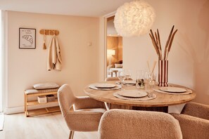 A dining area with a round wooden table set for four, surrounded by plush chairs. - 4P Modern Chalet with Private Sauna - Fenced Garden in a Wooded Area - BBQ (Putten)
