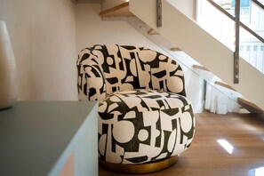 Une chaise moderne ornée d’un motif géométrique, placée près d’un escalier dans un espace intérieur bien éclairé.