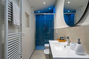 A modern bathroom with a glass-enclosed shower, a white sink with a soap dispenser, and a towel rack. - Relax Retreat in Historic Florence - Private Sauna & Hydromassage (Firenze)
