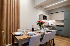 A modern dining area with a wooden table set for a meal, a microwave, and a kitchen in the background. - Relax Retreat in Historic Florence - Private Sauna & Hydromassage (Firenze)