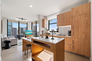 A modern kitchen with wooden cabinets, a marble countertop, and a city view through large windows. - The Crosby Worldcenter 2BR Palermo Home  (Miami)