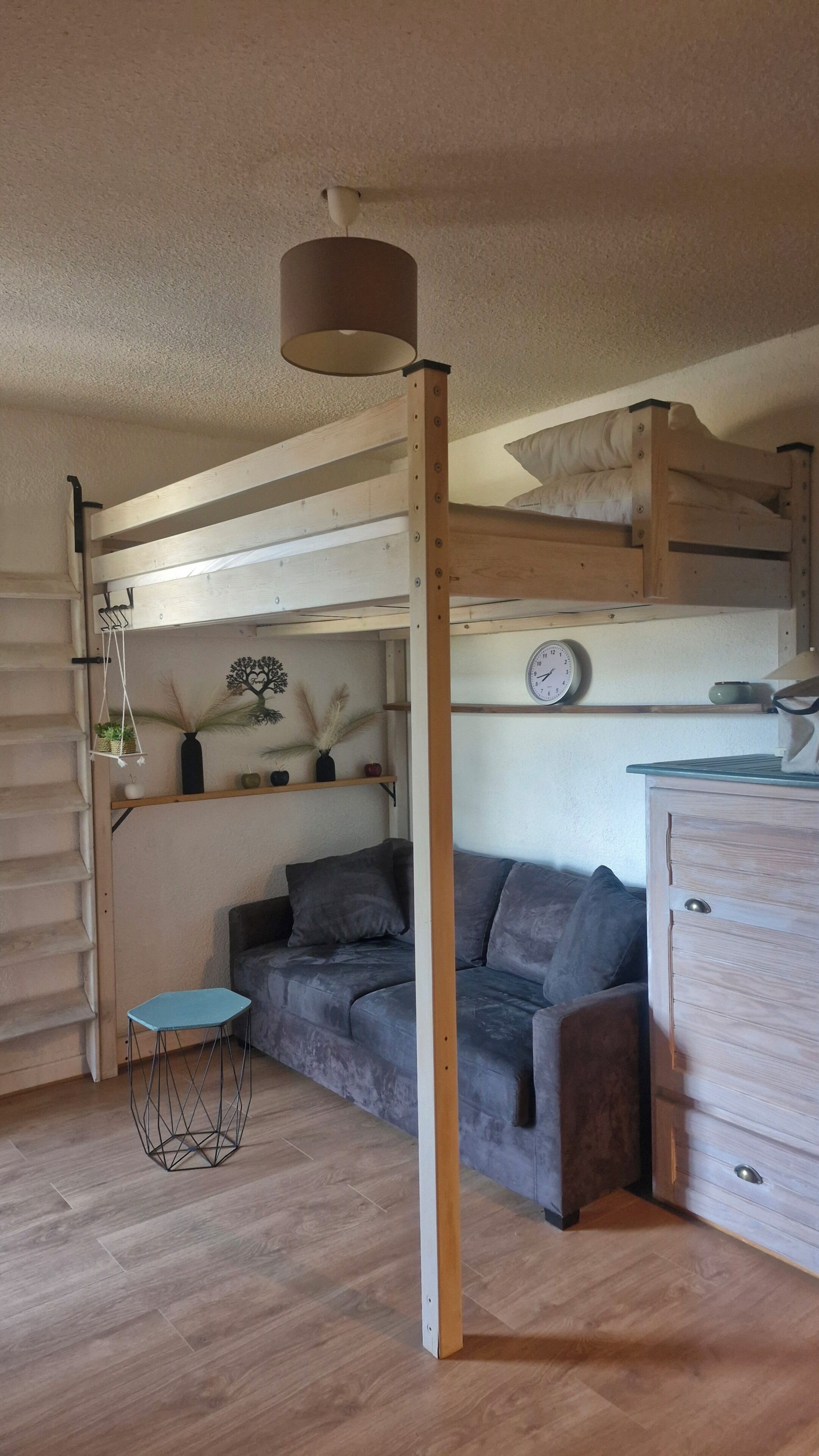 Una habitación compacta con literas, un sofá, una mesita y un aparador.