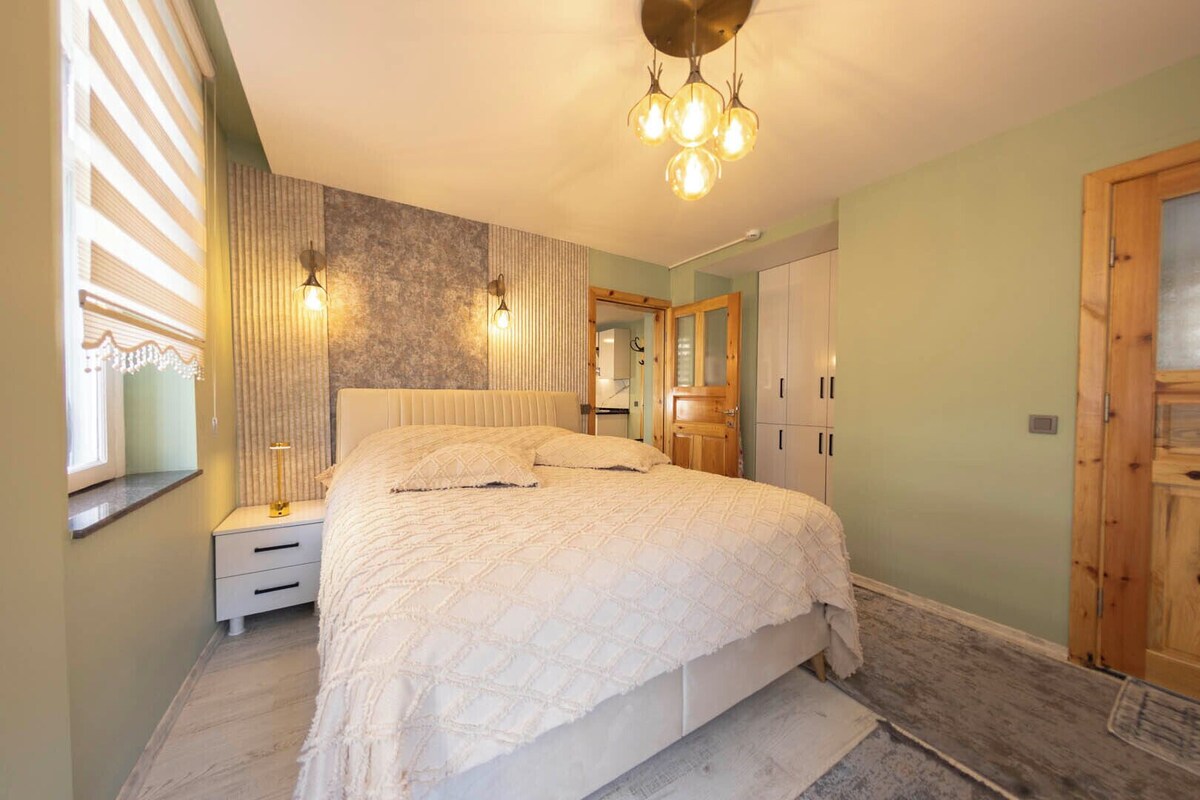 A bedroom with a bed, bedside tables, a mirror, a wardrobe, and a chandelier.