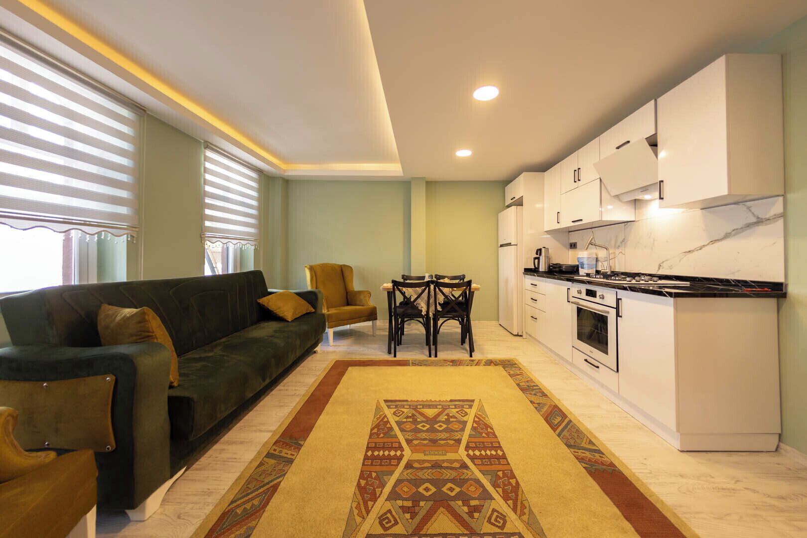 Una sala de estar moderna con un sofá, una mesa de comedor con sillas y una cocina con armarios y electrodomésticos.