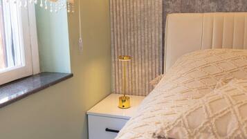 Un dormitorio con cama, una mesita de noche con lámpara, una ventana con cortinas y una pared con textura.