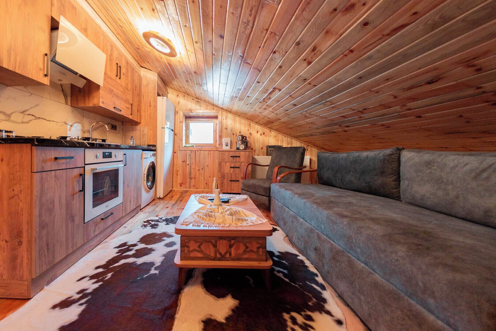 Un intérieur de chalet chaleureux et accueillant, avec une cuisine, un canapé et un tapis en peau de vache.