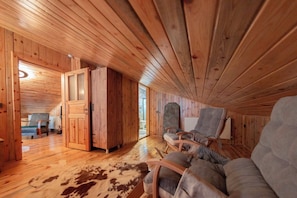 A wooden interior with a sofa, a chair, and a cowhide rug.