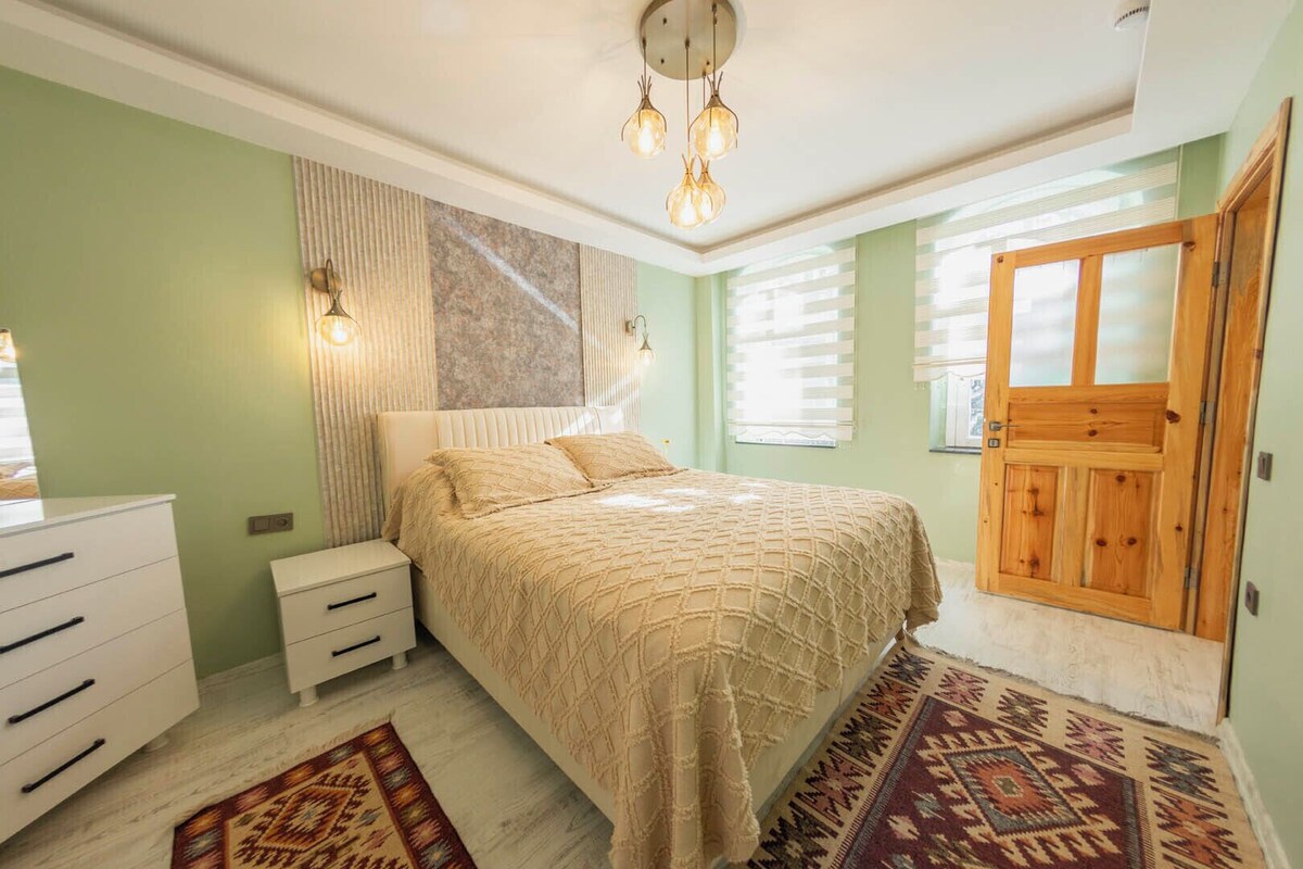 A bedroom with a bed, bedside tables, a wardrobe, and a patterned rug.