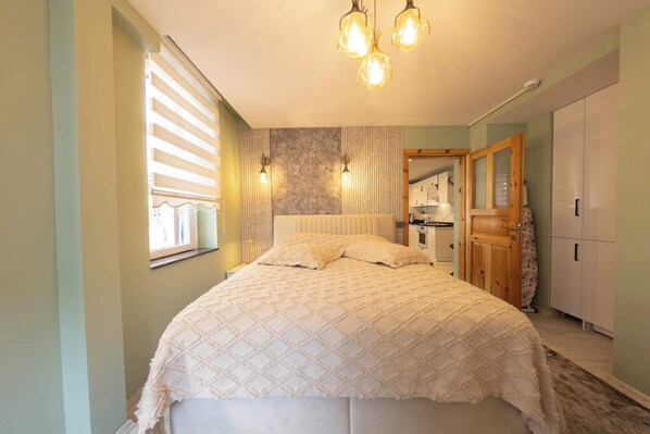 Un dormitorio con cama, una ventana con persianas, una lámpara de pared y un armario de madera.