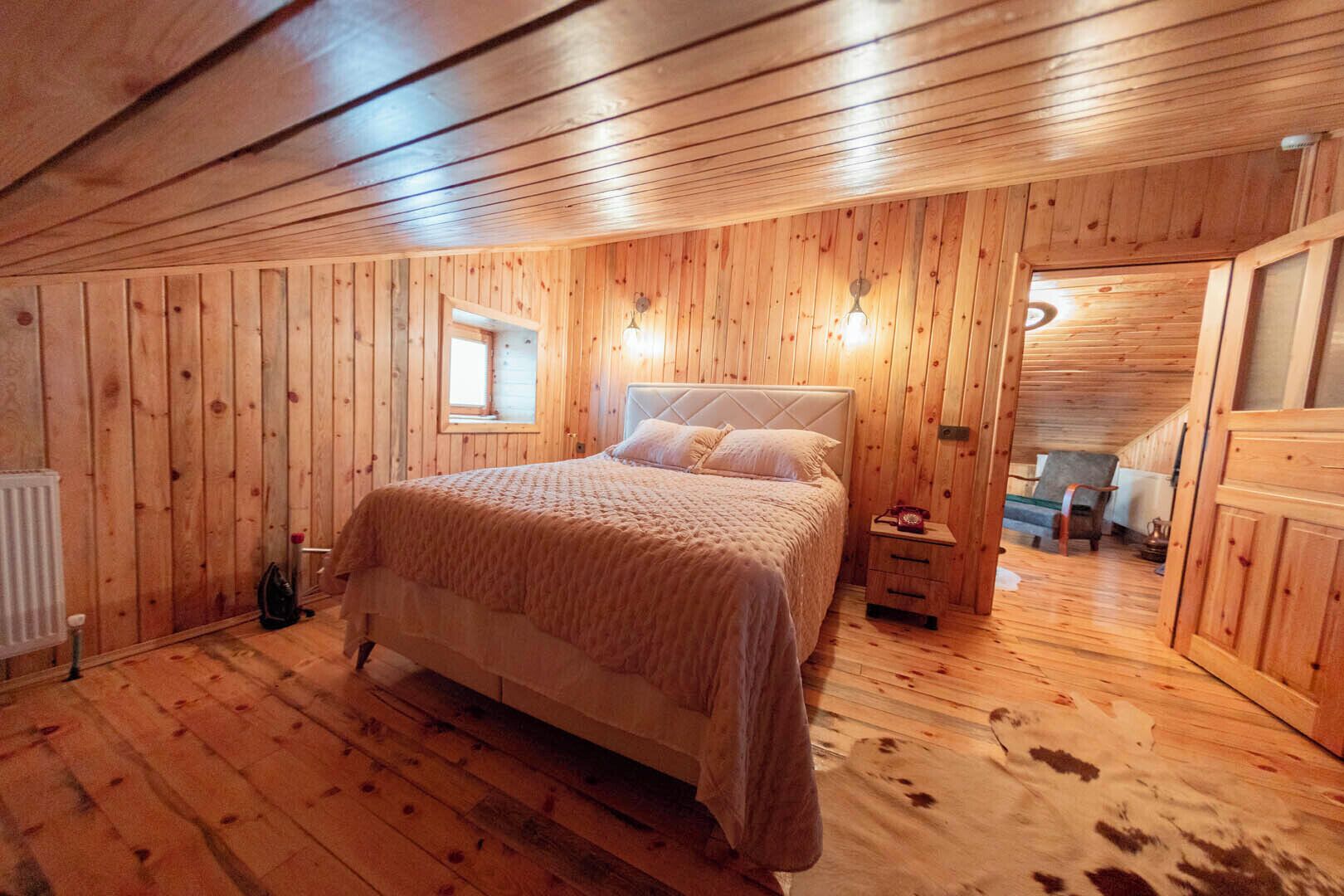 Un dormitorio con paneles de madera, una cama, una mesita de noche y una ventana.
