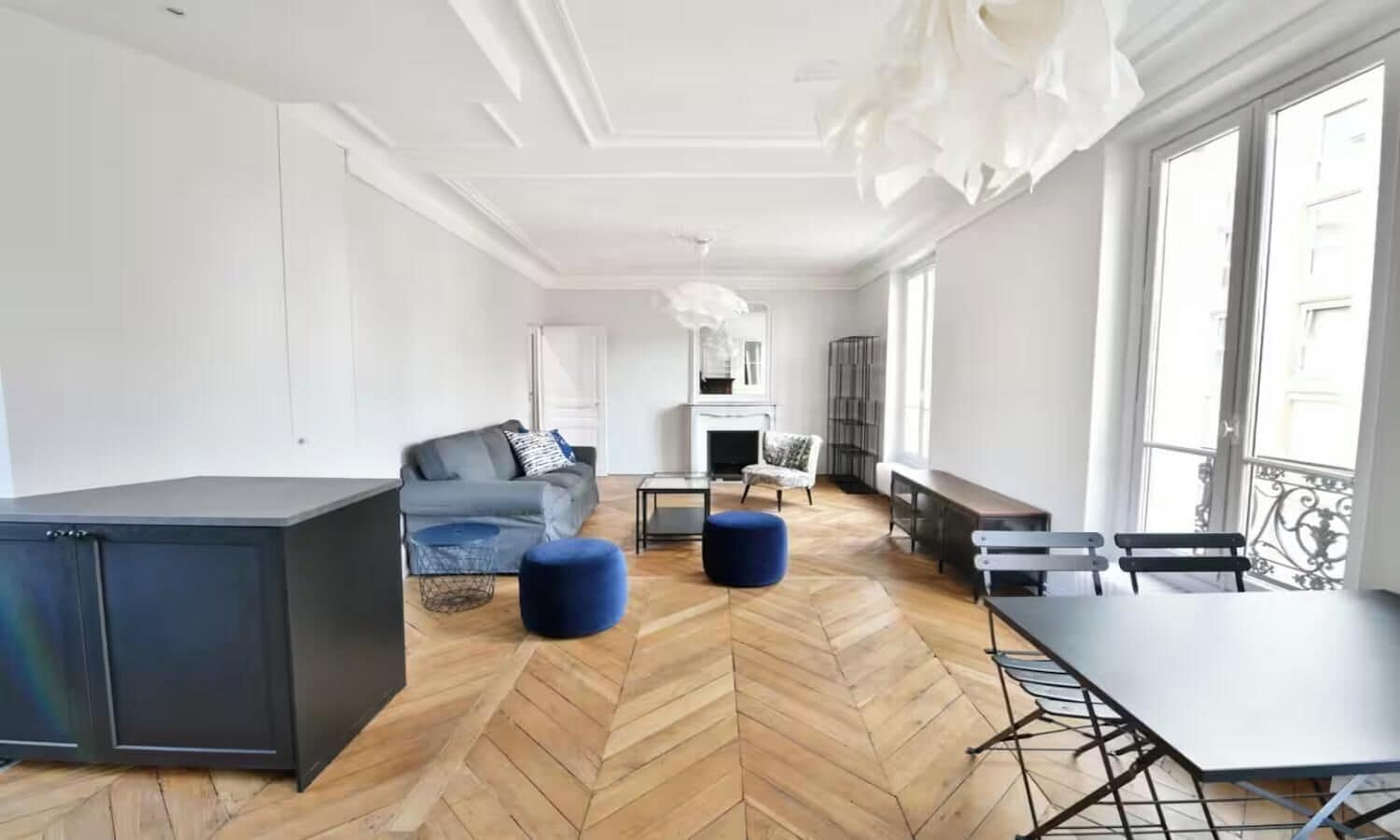 A spacious living area with a sofa, ottoman, and a dining table with benches.