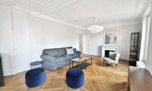 A modern living room with a grey sofa, a coffee table, and a patterned armchair. - COMBINING CLASSIC PARISIAN ARCHITECTURE WITH CONTEMPORARY COMFORT - 2 BEDROOM (Paris)