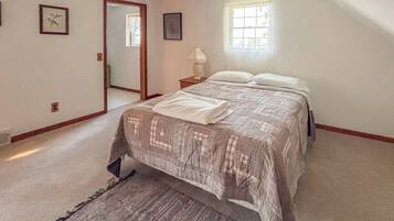 A bedroom with a bed, a nightstand, a window, and a door.