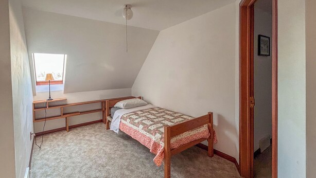 Quarto com uma cama de solteiro, escrivaninha e janela.