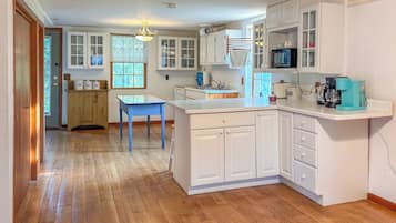 A kitchen with white cabinets, a blue table, and a wooden floor.