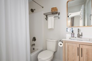 A bathroom with a bathtub, toilet, and sink. - Moultrie & Palmetto Suites | Walk to Bars (Charleston)