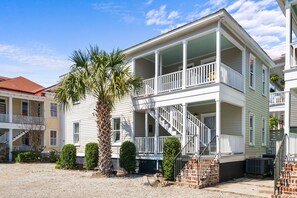 A two-story house with a balcony, a staircase, and a palm tree in the yard. - Moultrie & Palmetto Suites | Walk to Bars (Charleston)