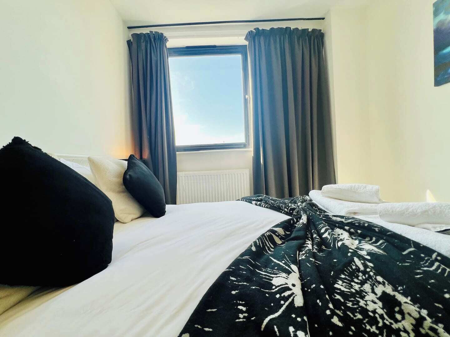 A hotel room with a bed, a window with curtains, and a radiator.